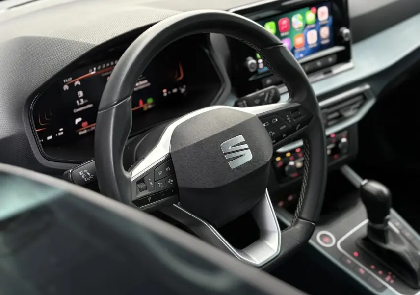 Vue rapprochée du volant multifonction noir et tableau de bord digital du SEAT Arona 2025, intérieur moderne.