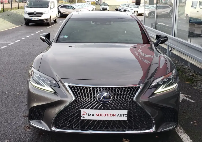 Vue frontale d'une Lexus LS 500H gris manganèse avec calandre distinctive et feux LED allumés.