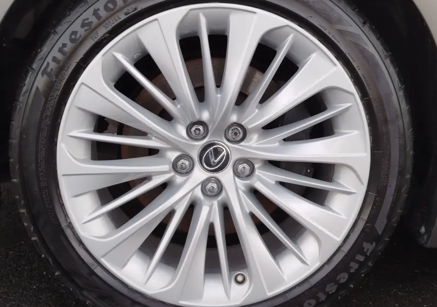 Gros plan sur la jante alliage argentée de la Lexus LS 500H 2020 avec logo Lexus au centre et pneu Firestone.