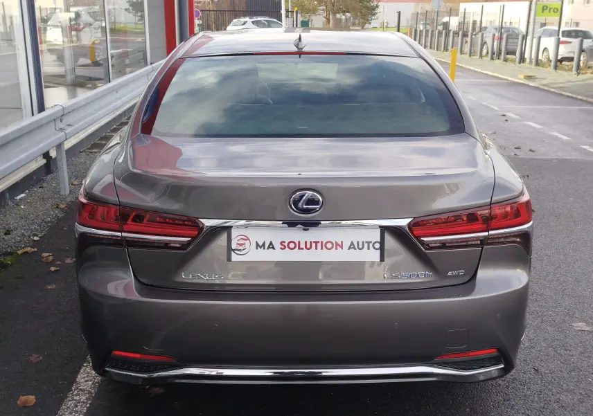 Vue arrière d'une Lexus LS 500h gris manganèse 2020 avec feux LED et badge AWD visible sur un parking.