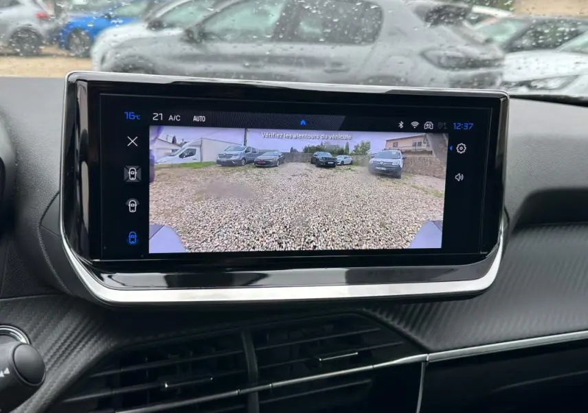 Écran tactile central du Peugeot 2008 Hybrid 145 Allure montrant la caméra de recul avec vue sur un parking gravillonné.