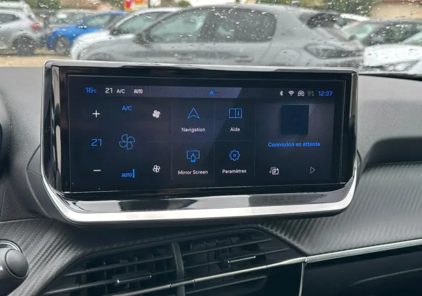 Écran tactile central du tableau de bord d’un Peugeot 2008 Hybrid gris, affichant les commandes de climatisation et navigation.