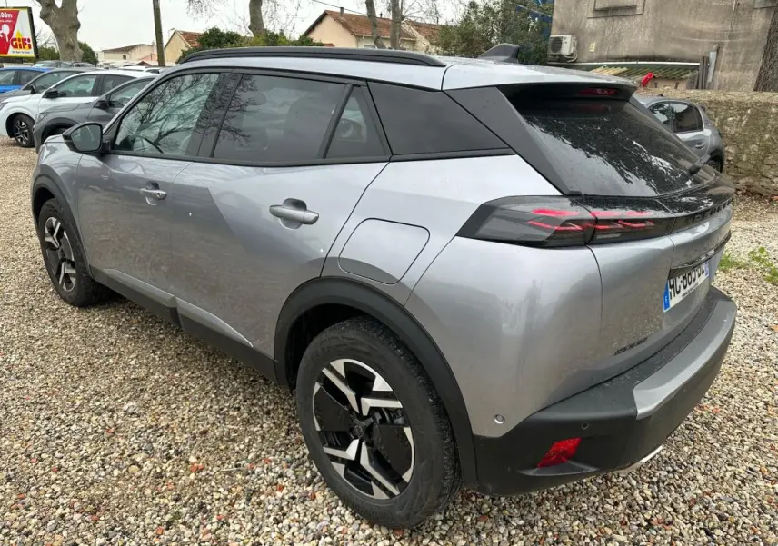 Vue 3/4 arrière droite d’un Peugeot 2008 Hybrid gris avec jantes alliage 17 pouces et toit noir.