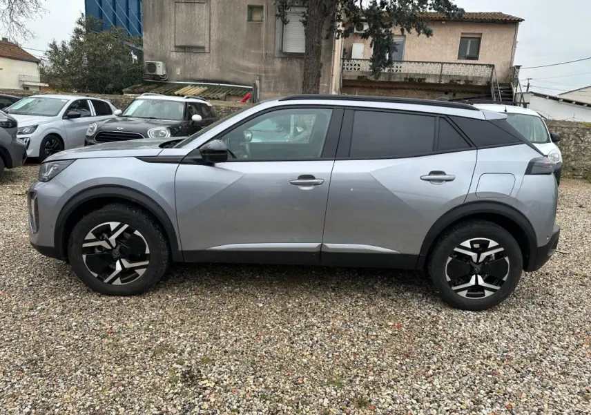 Vue de profil côté gauche d'un Peugeot 2008 Hybrid gris avec jantes alliage noires et toit noir contrasté.
