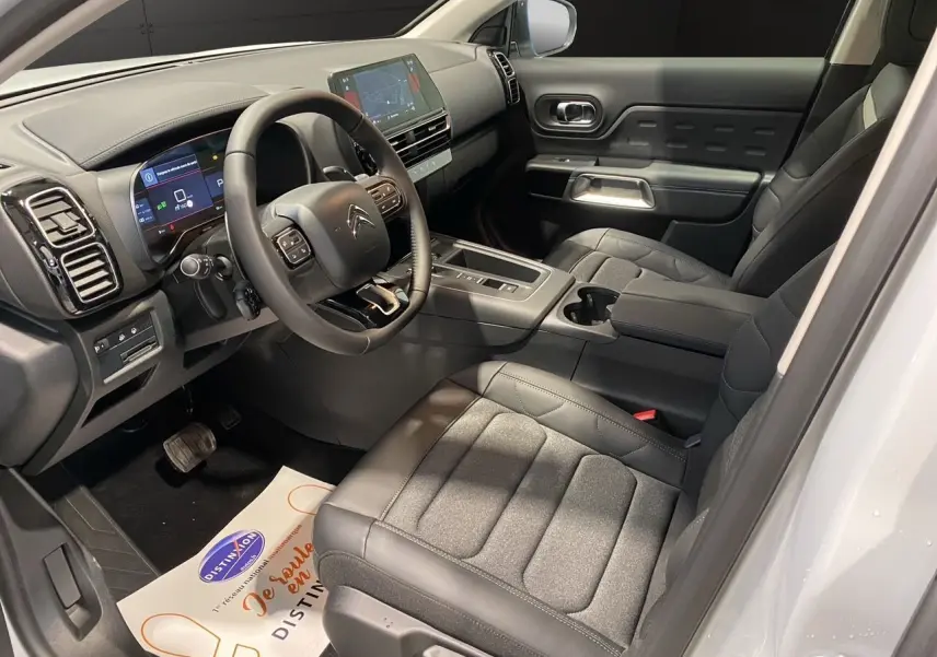 Intérieur noir du Citroën C5 Aircross 2024 vu côté conducteur, avec tableau de bord digital et sièges tissu cuir.