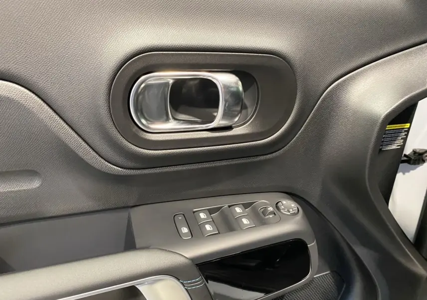 Poignée de porte intérieure côté conducteur en plastique noir avec commandes électriques sur une Citroën C5 Aircross blanc et noir.