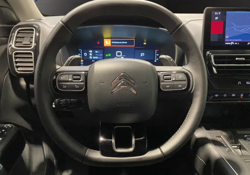 Vue rapprochée du volant cuir noir de la Citroën C5 Aircross 2024 avec tableau de bord numérique et écran tactile.
