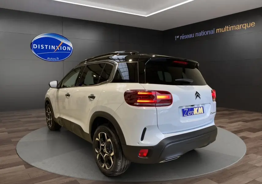 Vue 3/4 arrière droite du Citroën C5 Aircross blanc et noir 2024 avec feux allumés en showroom.