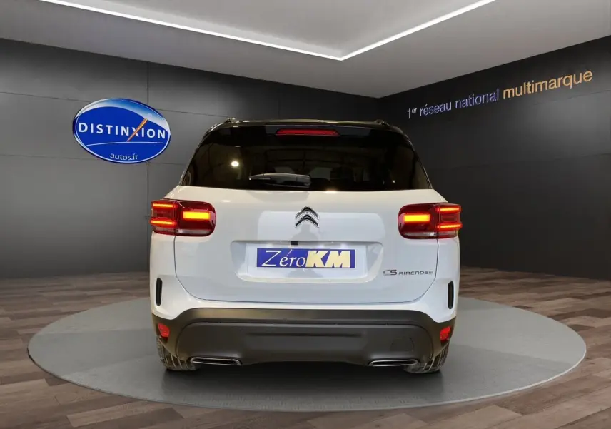 Vue arrière du Citroën C5 Aircross blanc et noir de 2024 avec feux allumés dans un showroom.