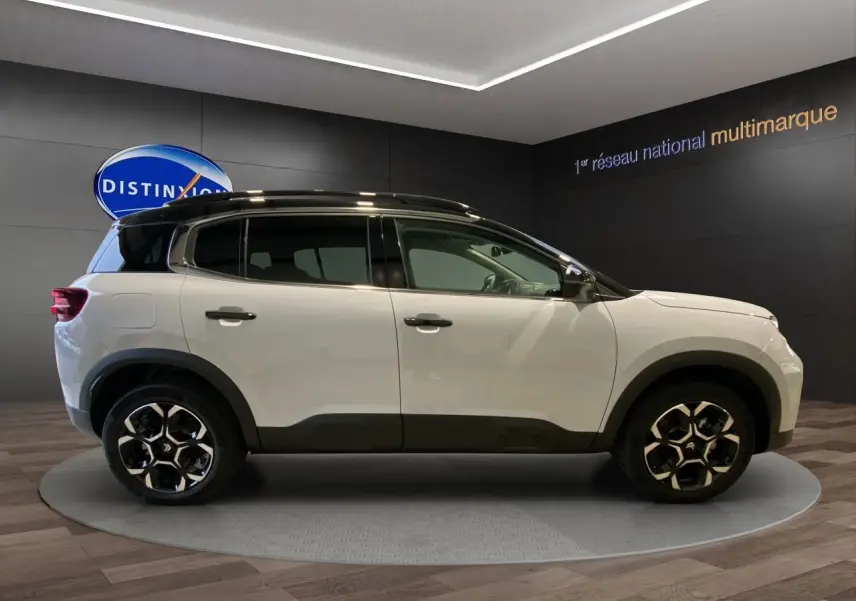 Profil côté droit du Citroën C5 Aircross 2024 blanc et noir avec jantes noires et toit contrasté en showroom.