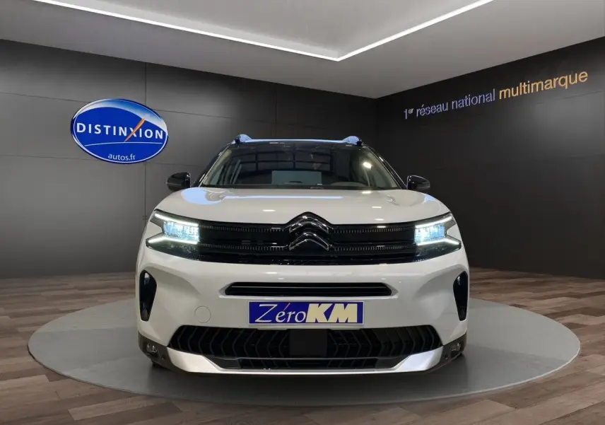 Vue frontale d'un Citroën C5 Aircross blanc et noir 2024 avec phares LED allumés en showroom.