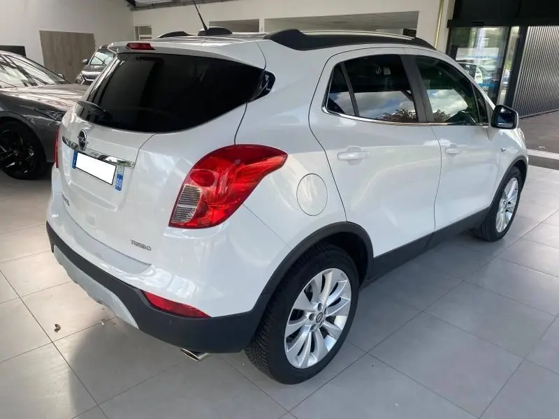 Vue 3/4 arrière droite d'un Opel Mokka blanc de 2017, avec vitres teintées et jantes alliage en showroom.