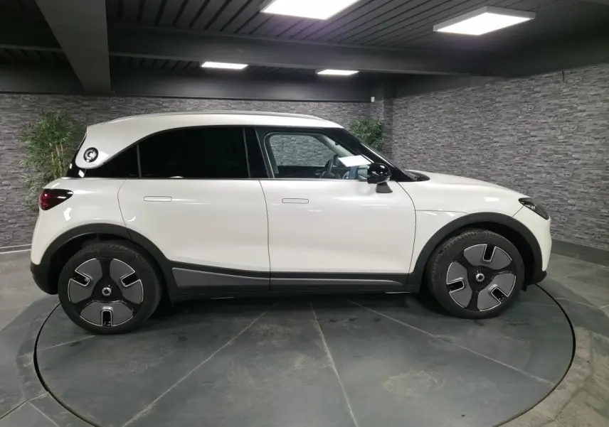 Vue de profil côté gauche d'une Smart #1 électrique blanche avec jantes spécifiques et toit blanc contrasté.