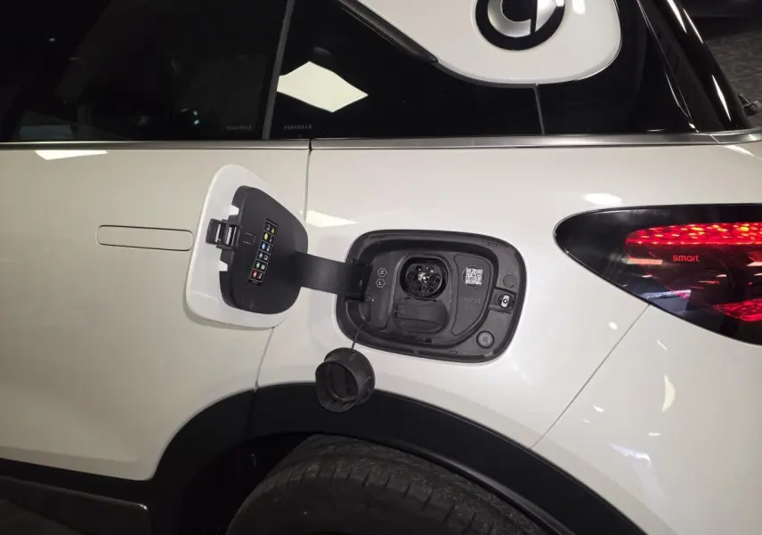 Prise de recharge ouverte côté gauche arrière d'une Smart #1 blanche avec feu arrière LED visible.