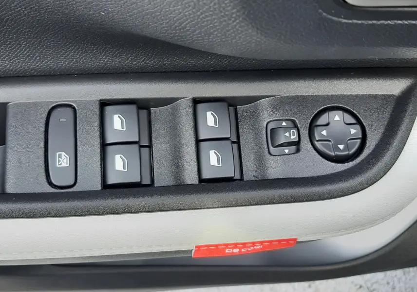 Vue rapprochée des commandes de lève-vitres et réglages des rétroviseurs sur la portière côté conducteur d'une Citroën C3 Aircross hybride vert Montana toit blanc.