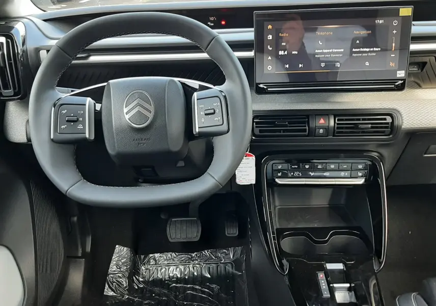Vue intérieure frontale du tableau de bord et volant noir du Citroën C3 Aircross hybride 2026 avec écran tactile et console centrale brillante.