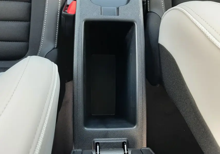 Vue plongeante sur la console centrale noire entre sièges avant en cuir beige et tissu noir du Citroën C3 Aircross hybride 2026.