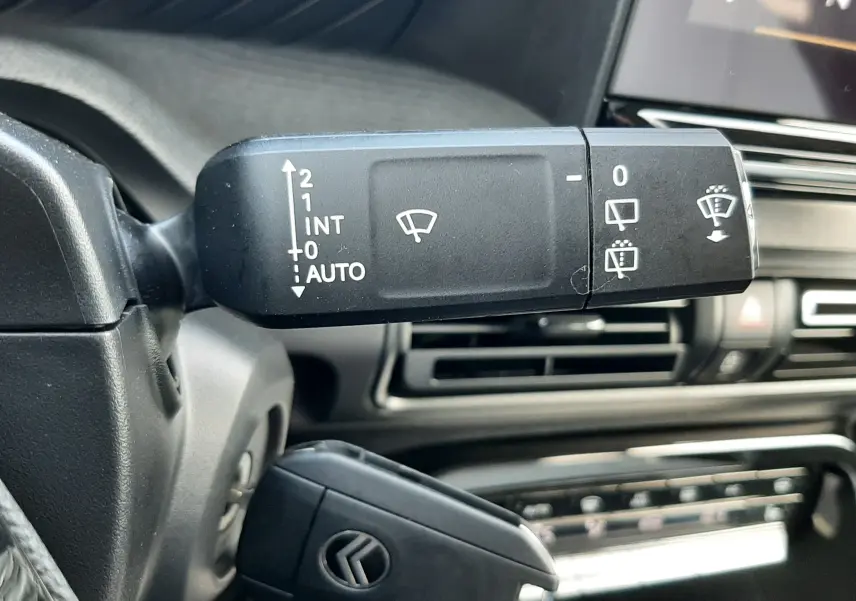 Gros plan sur la commande des essuie-glaces et la clé de contact dans l’habitacle noir du Citroën C3 Aircross hybride 2026.