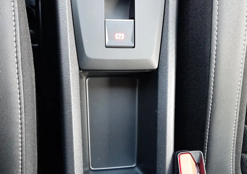 Vue plongeante sur la console centrale noire du Citroën C3 Aircross hybride 2026, avec frein à main électronique et ceintures rouges.