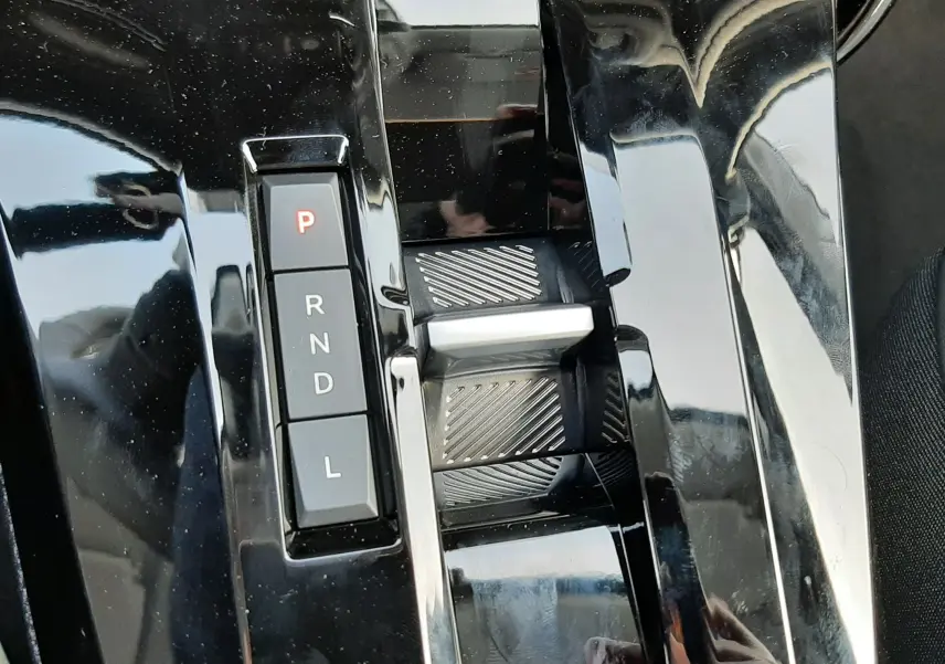 Gros plan sur la console centrale noire brillante de la Citroën C3 Aircross hybride, avec levier de vitesses automatique et boutons P, R, N, D, L.