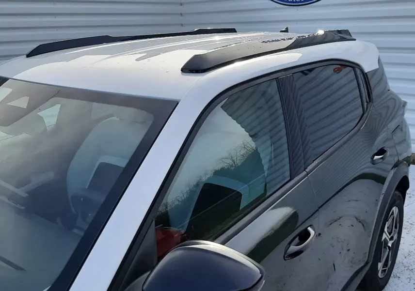 Vue 3/4 avant droit du Citroën C3 Aircross hybride 2026 vert Montana avec toit blanc opale et barres de toit noires.