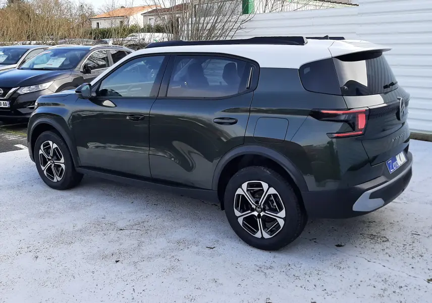 Vue 3/4 arrière droite du Citroën C3 Aircross hybride 2026 vert Montana avec toit blanc et jantes bi-ton.