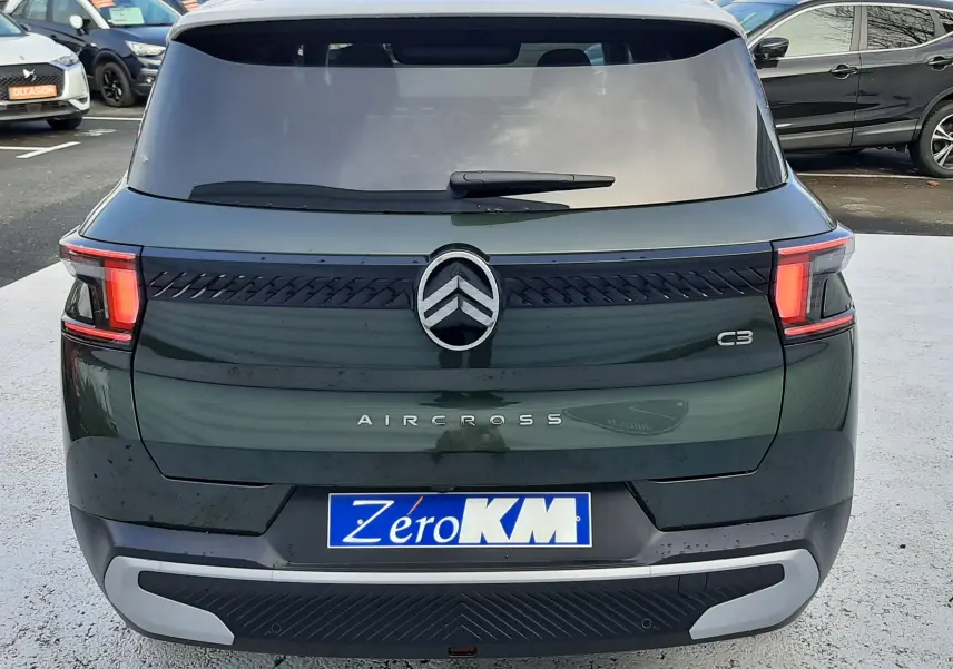 Vue arrière d'un Citroën C3 Aircross hybride 2026 vert Montana avec toit blanc opale, feux arrière LED et logo central.