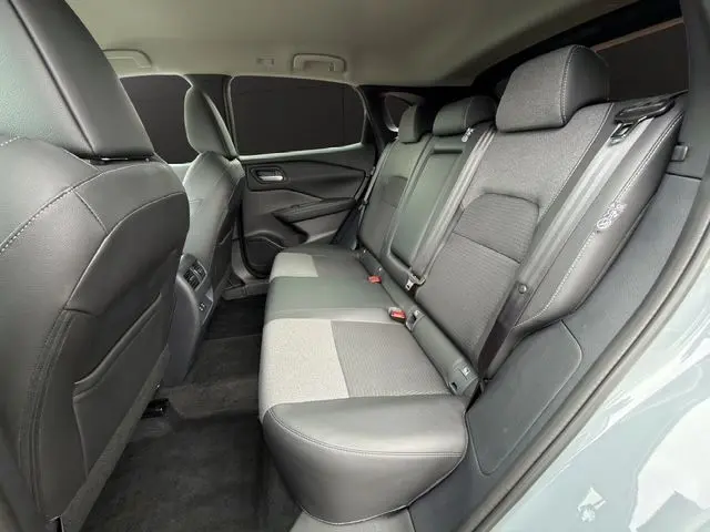 Vue intérieure arrière côté droit du Nissan Qashqai 2025 en Ceramic Grey, sièges bicolores cuir et tissu gris.