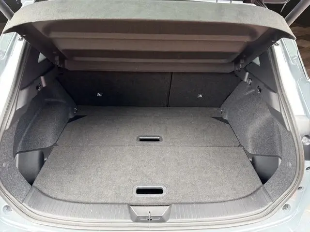 Vue du coffre ouvert du Nissan Qashqai 2025 Ceramic Grey, montrant l'espace de chargement plat et tapissé en tissu gris.
