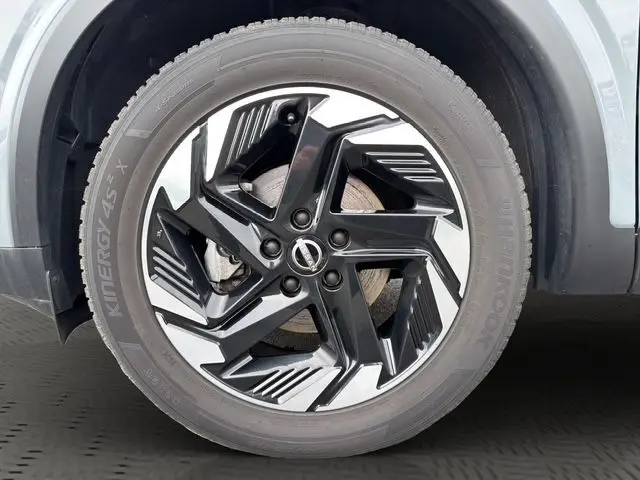 Gros plan sur la roue avant droite du Nissan Qashqai 2025 Ceramic Grey avec jante alliage noire et argentée au design moderne.