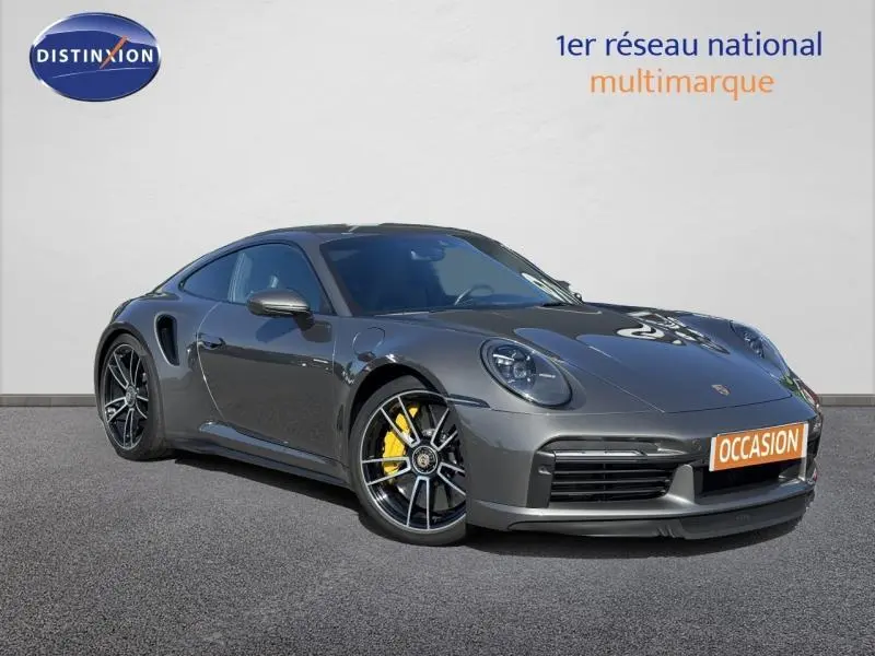 Vue 3/4 avant droite d'une Porsche 911 Turbo S grise avec jantes noires et étriers de frein jaunes.