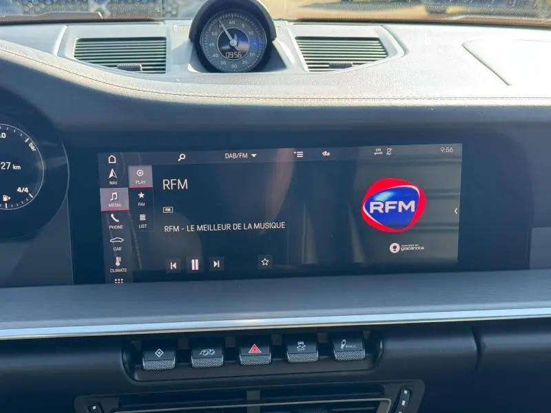 Vue rapprochée de l’écran tactile central noir du tableau de bord de la Porsche 911 Turbo S 2020 affichant la radio RFM.