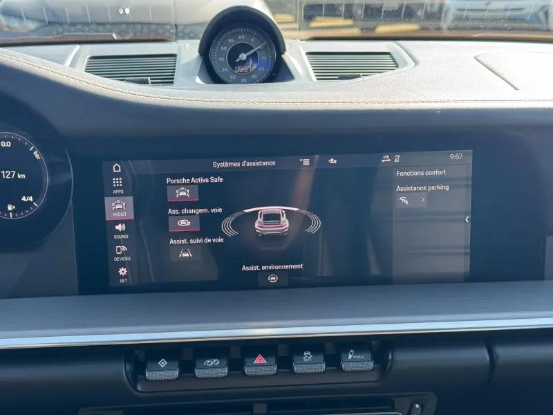 Vue rapprochée du tableau de bord noir de la Porsche 911 Turbo S 2020, avec écran tactile affichant les aides à la conduite.