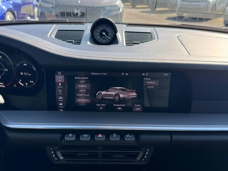 Vue intérieure du tableau de bord noir de la Porsche 911 Turbo S 2020 avec écran central affichant les réglages du véhicule.