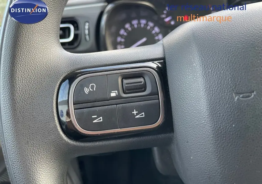 Gros plan sur les commandes au volant côté gauche de la Citroën C3 gris platinium 2023.