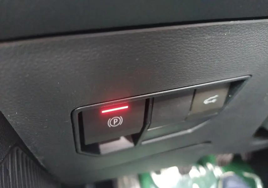 Gros plan sur le bouton de frein à main électronique allumé dans l'habitacle du Dacia Bigster gris schiste.