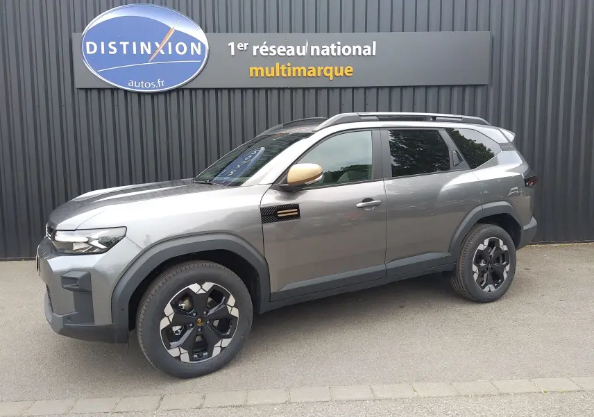 SUV Dacia Bigster gris schiste en vue de profil côté gauche, avec rétroviseur doré et jantes noires distinctives.