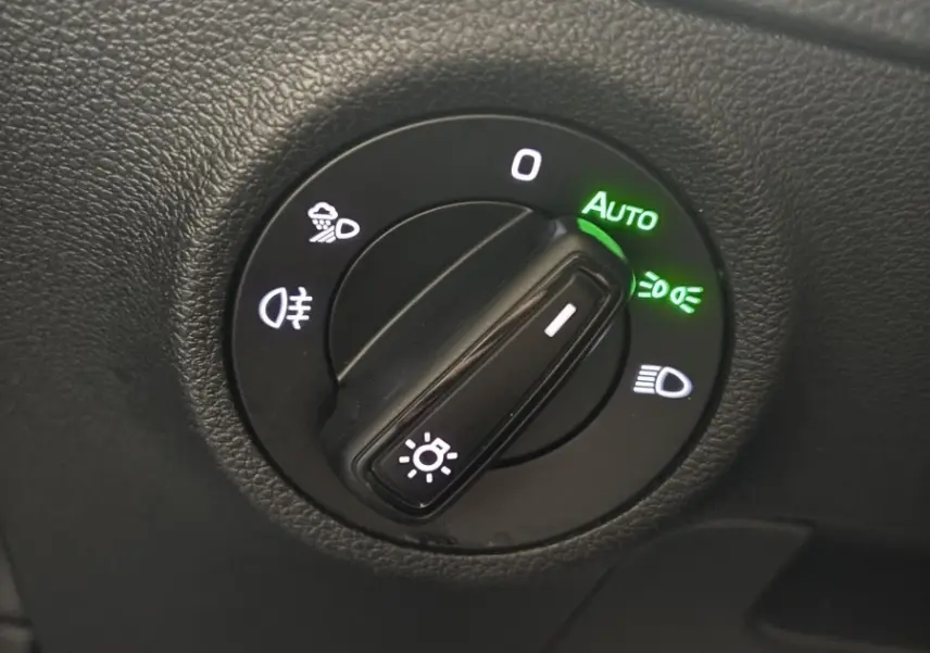 Gros plan sur la commande d'éclairage avec mode automatique activé dans l'habitacle noir du Skoda Karoq 2025.