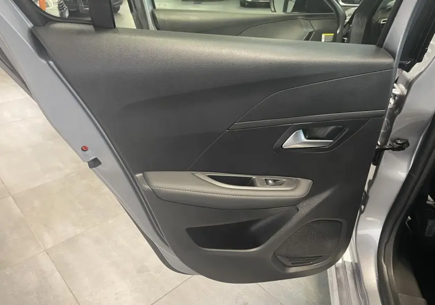 Porte arrière droite ouverte d'une Peugeot 208 2025 gris Artense avec garniture noire et accoudoir gris clair surpiqué