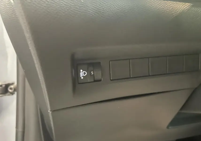Gros plan sur le réglage des phares à gauche du tableau de bord d'une Peugeot 208 Gris Artense 2025.