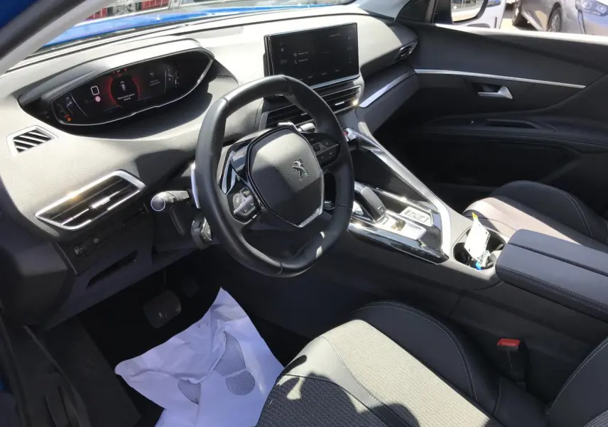 Vue intérieure côté conducteur du Peugeot 3008 2022 bleu Iron, avec volant compact et écran tactile central.