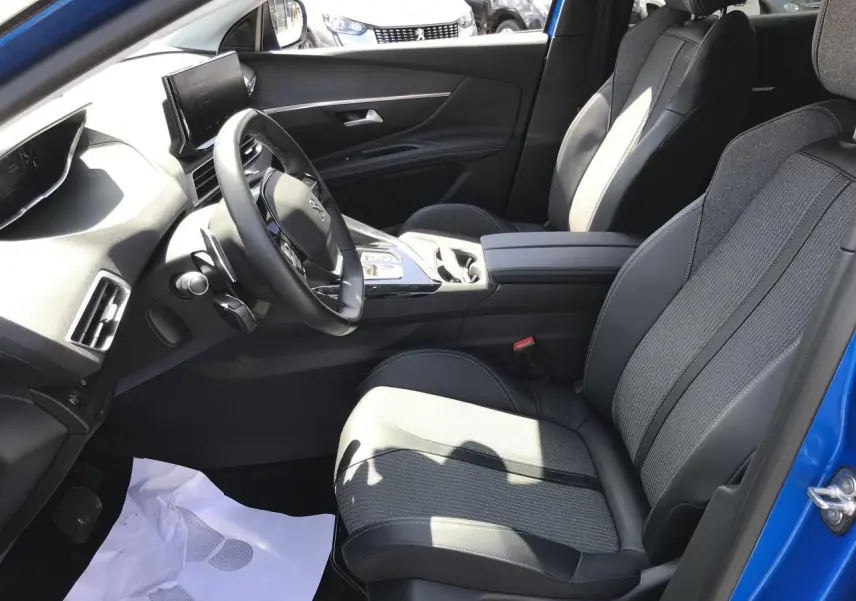 Vue intérieure côté conducteur du Peugeot 3008 bleu Iron 2022, mettant en valeur les sièges TEP et tissu et le volant cuir fleur.