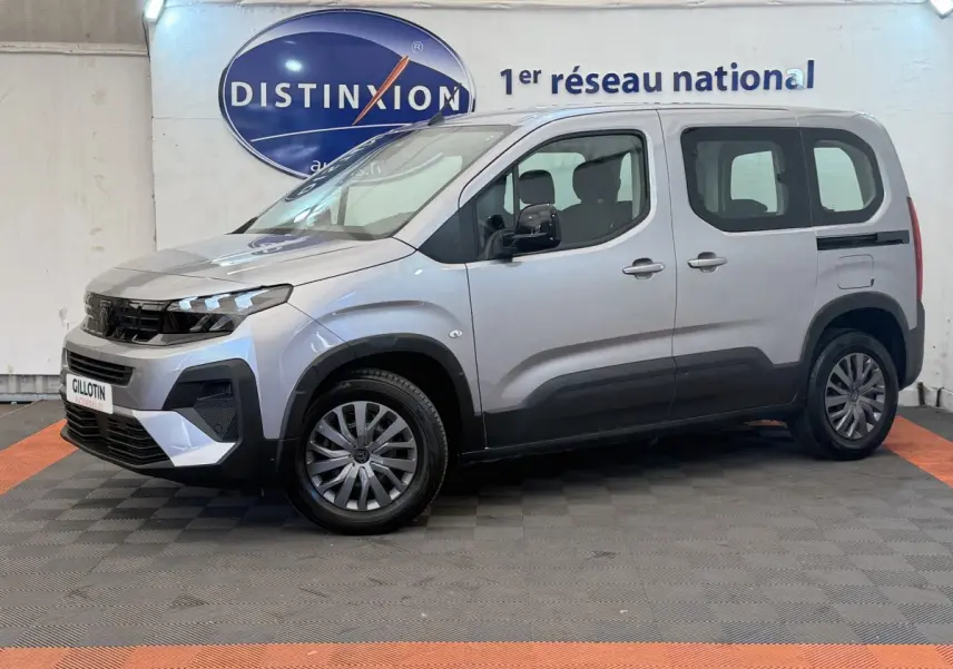 Peugeot Rifter gris clair vue de profil côté gauche, avec calandre noire et jantes alliage, en intérieur showroom.
