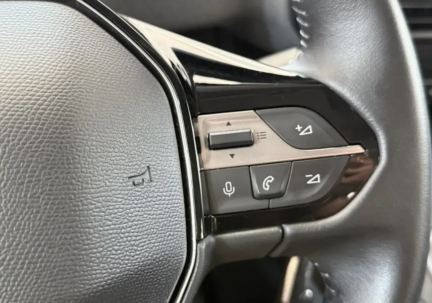 Gros plan sur le volant cuir multifonctions du Peugeot Rifter 2024, boutons de commande audio et téléphone visibles.