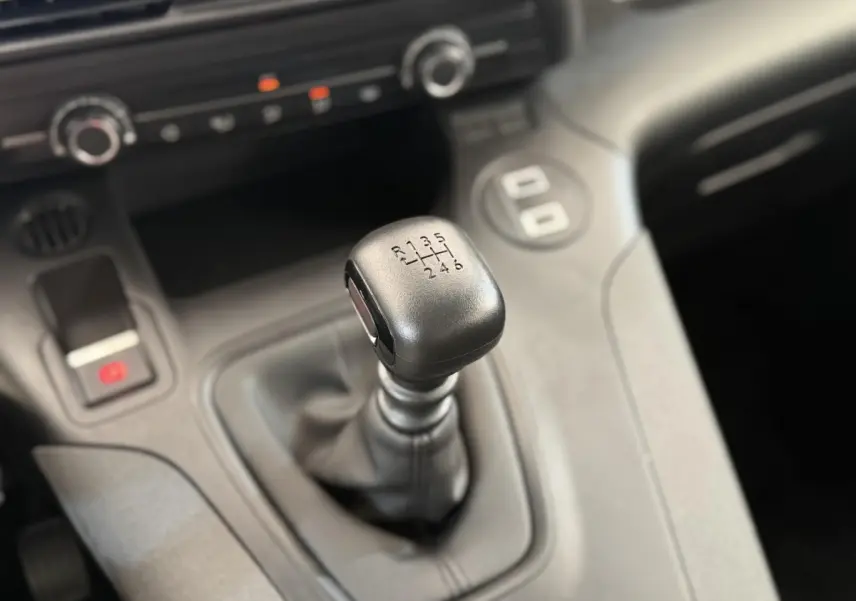 Le levier de vitesses manuel noir du Peugeot Rifter 1.5 BlueHDi 100, vue rapprochée de l'intérieur.