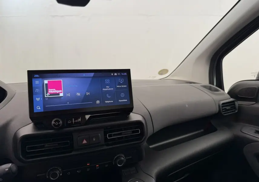 Vue intérieure côté passager du tableau de bord gris clair du Peugeot Rifter 2024 avec écran tactile central allumé.