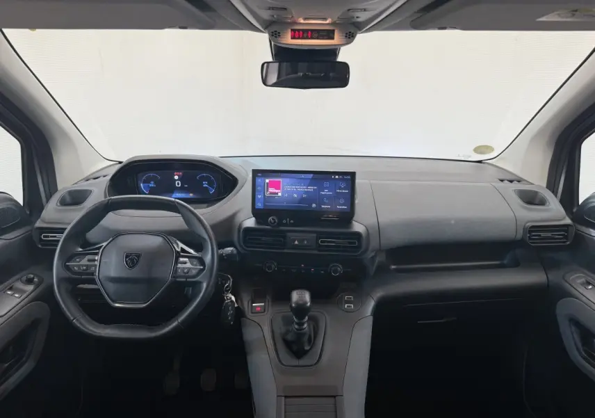 Vue intérieure frontale du tableau de bord gris du Peugeot Rifter 2024 avec volant cuir multifonctions et écran tactile central.