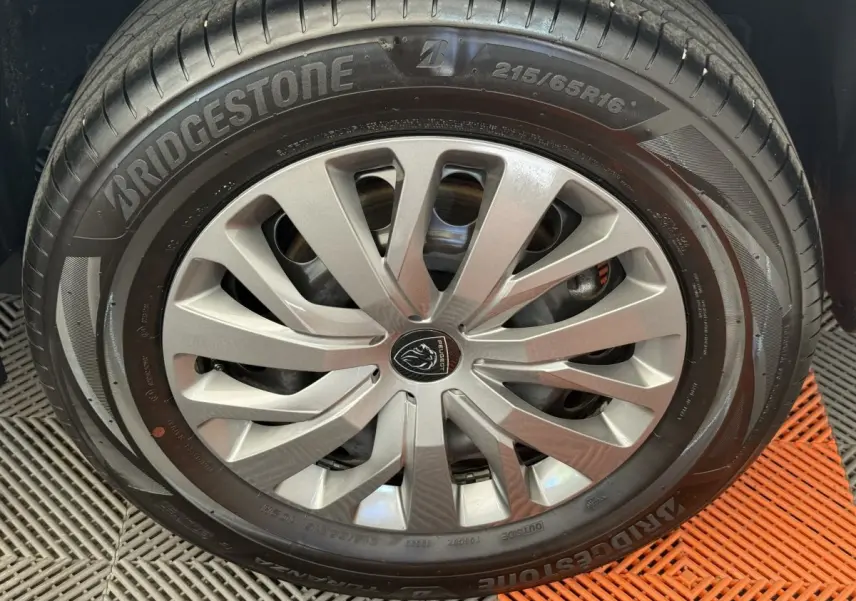 Gros plan sur la roue avant droite du Peugeot Rifter gris clair 2024 avec jante alliage et pneu Bridgestone.