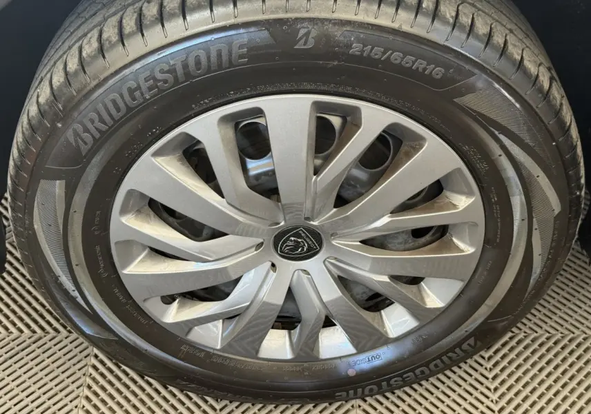 Gros plan sur la roue avant droite du Peugeot Rifter gris clair, jante alliage et pneu Bridgestone visible.