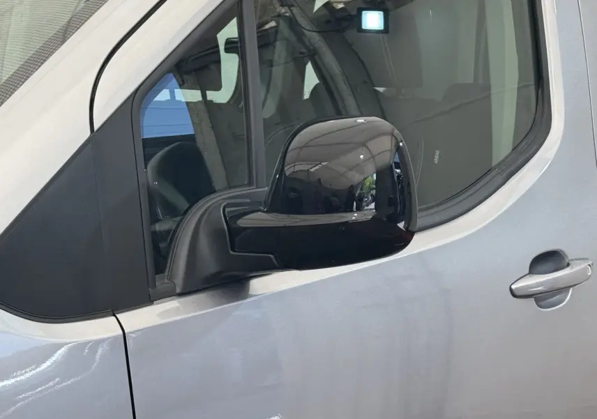 Vue rapprochée du rétroviseur noir côté gauche sur la porte gris clair du Peugeot Rifter 2024.
